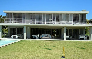 Single-storey glazed house with lawn and pool