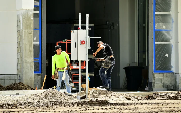 Two technicians installing an electrical distribution panel on site